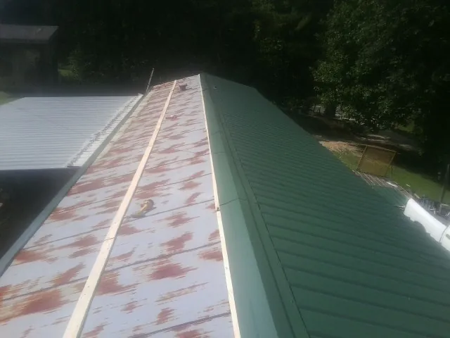 Old rusted panels beside newly installed green metal roofing — Wind Damage Roof Repair by Roofing Brothers in Saylorsburg