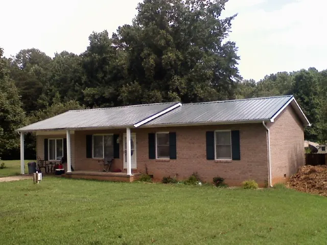 Gray metal roof on a brick ranch house with a side carport in Saylorsburg