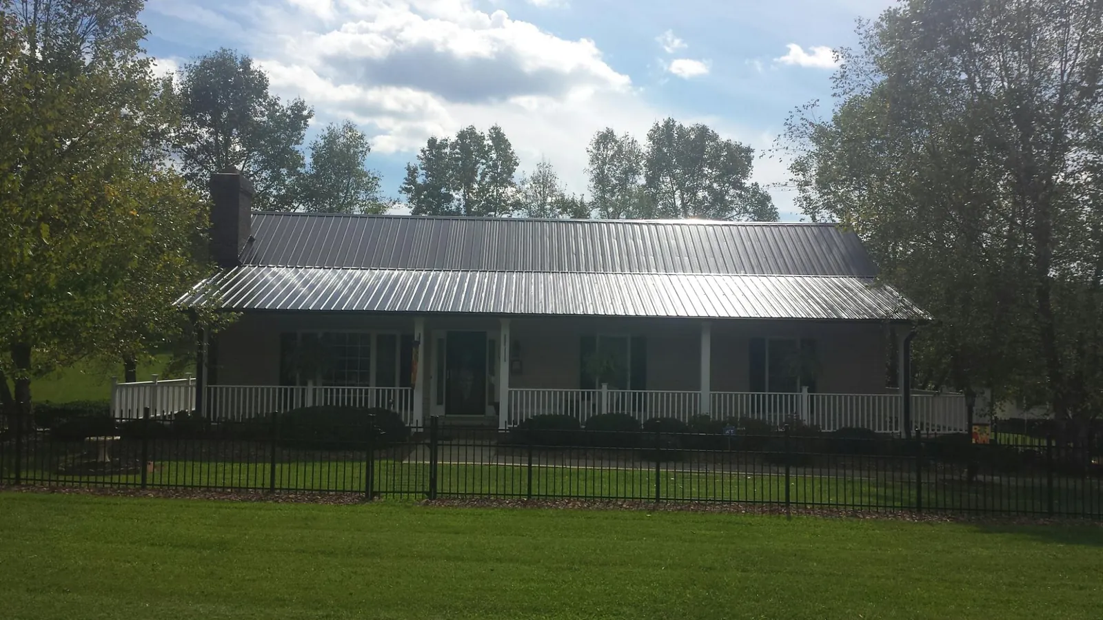 Gray metal roof on a brick ranch with a full width front porch — Gutter Guard Installation work by our crew in Saylorsburg