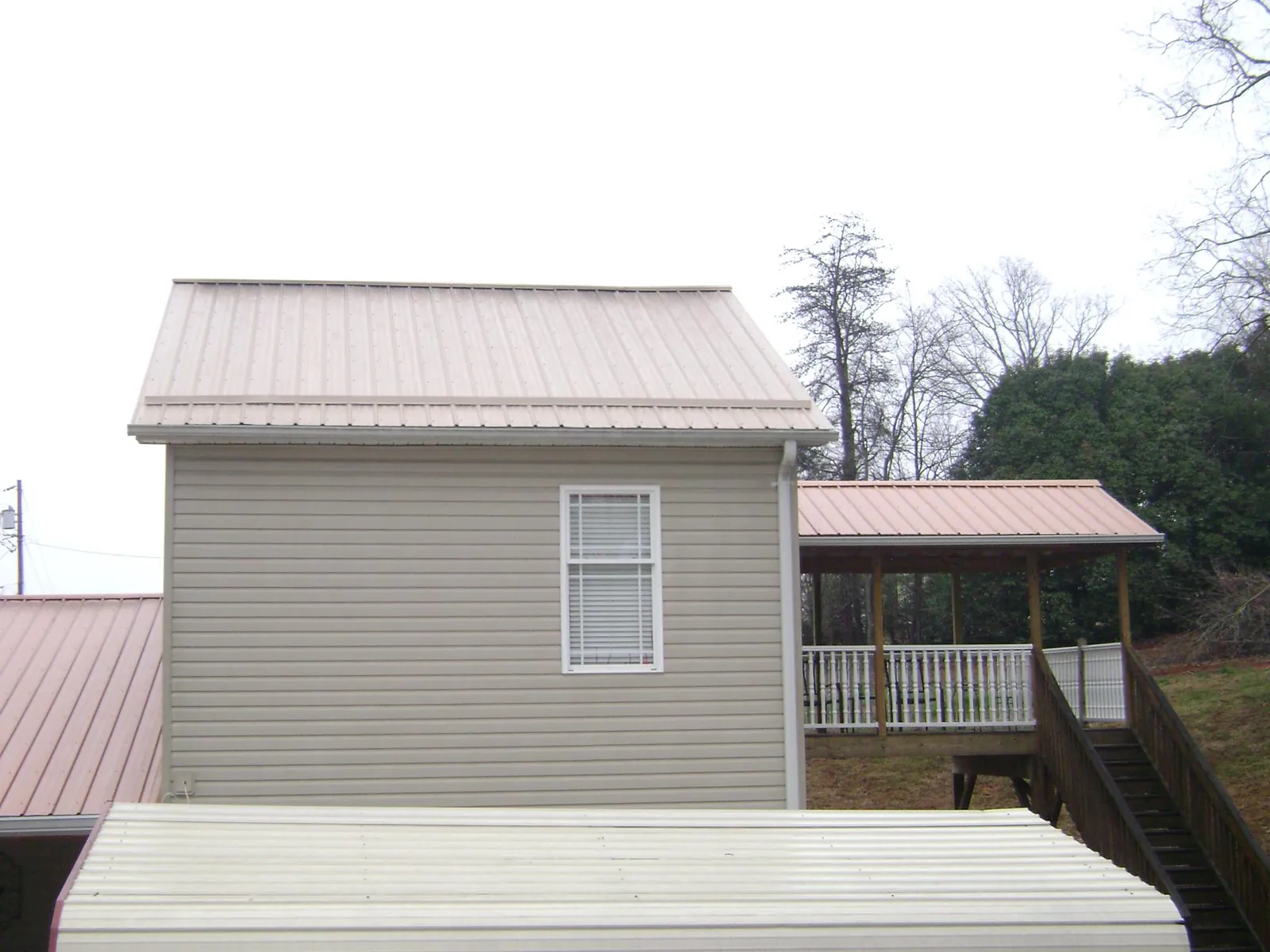 Tan metal roofs on a two story addition and attached porch, from a Roof Replacement job in Saylorsburg