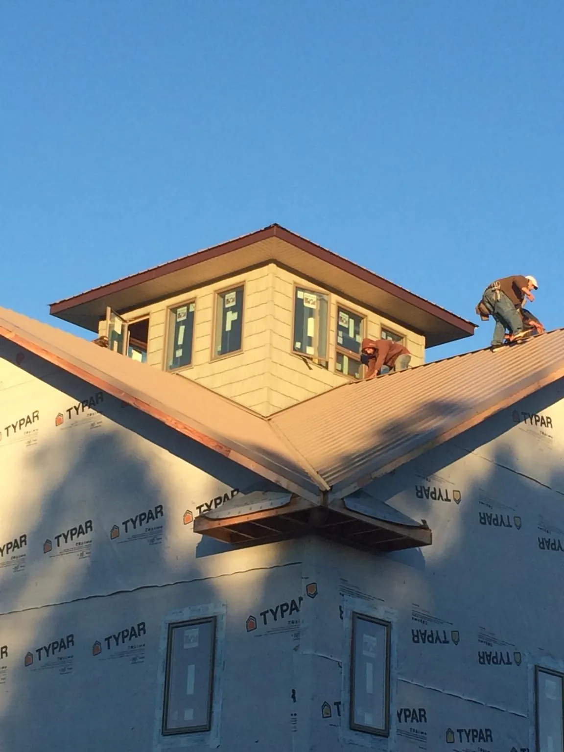 Roofers working around a rooftop cupola on a new metal roof at sunset — Roof Waterproofing in Saylorsburg by Roofing Brothers